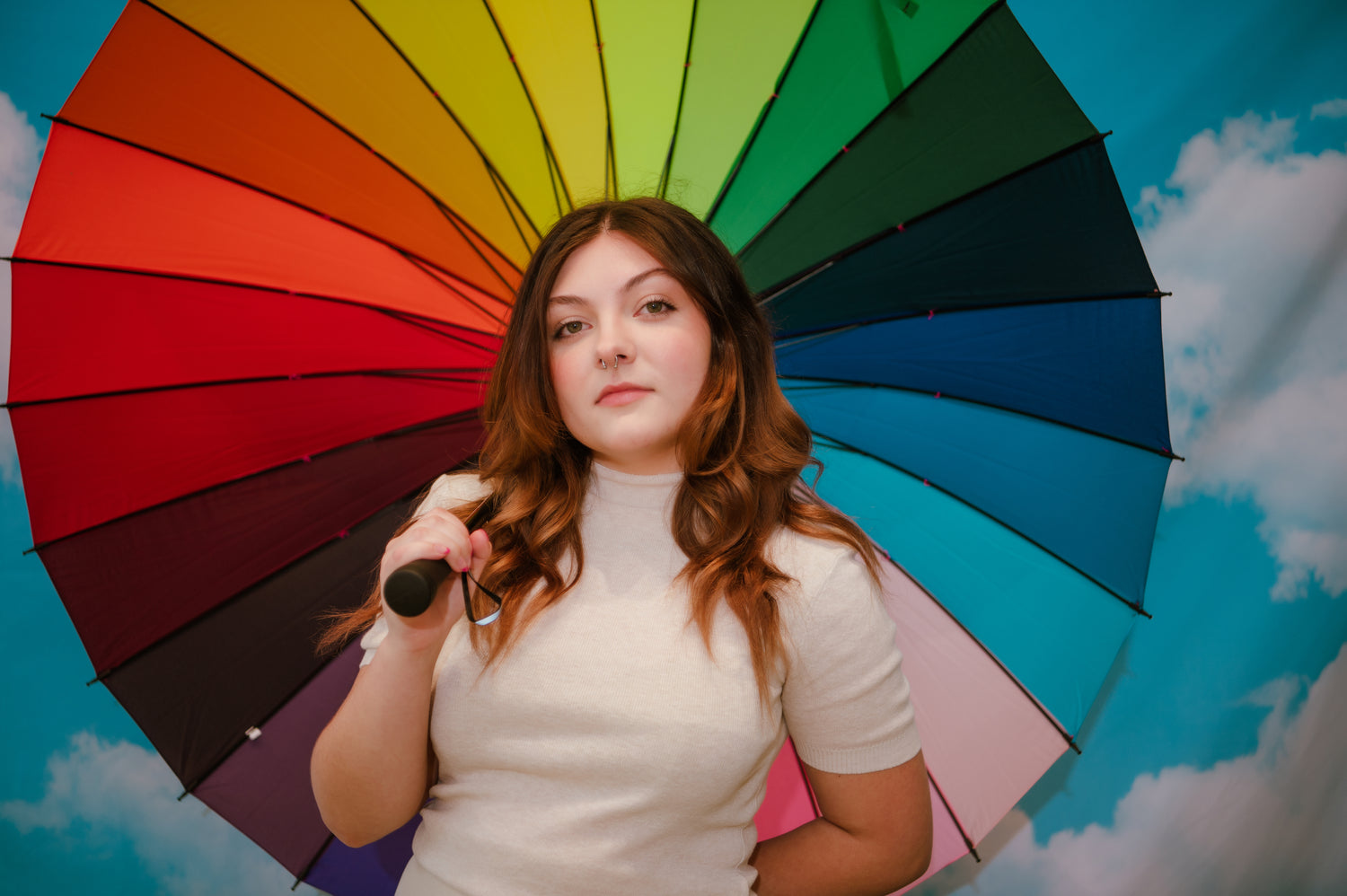 rin stares at the camera holding a full rainbow spectrum umbrella. image by jennifer alsabrook-turner of bang images for basic.'s 2022 pride campaign.
