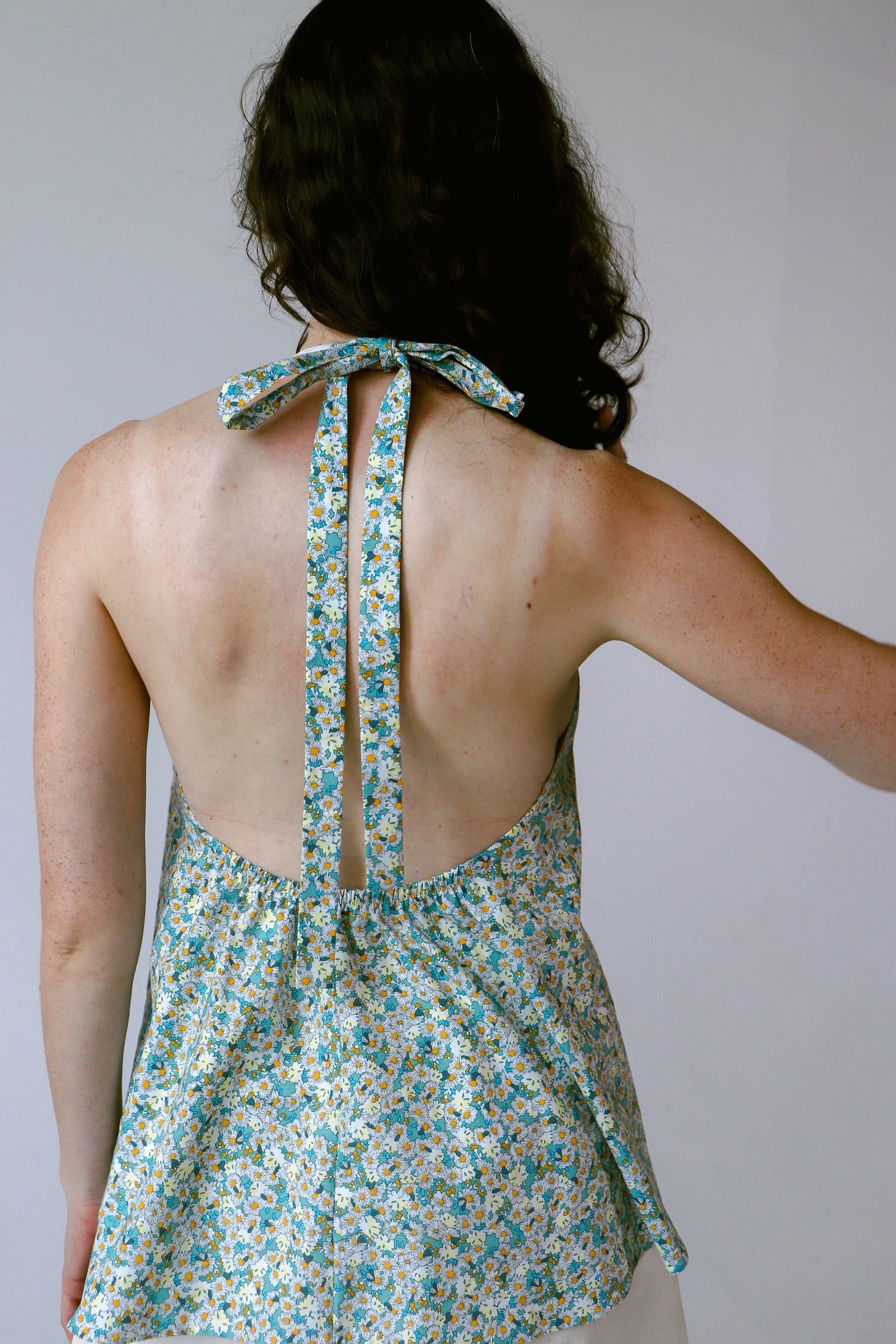 Woman wearing a floral halter top against a plain background