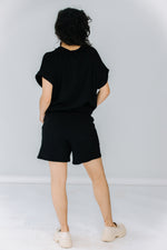 gabby wears the corinne collection siena shorts in black with the ava tunic in black and alohas trailblazer loafers.