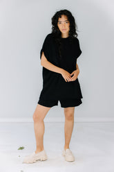 gabby wears the corinne collection siena shorts in black with the ava tunic in black and alohas trailblazer loafers.