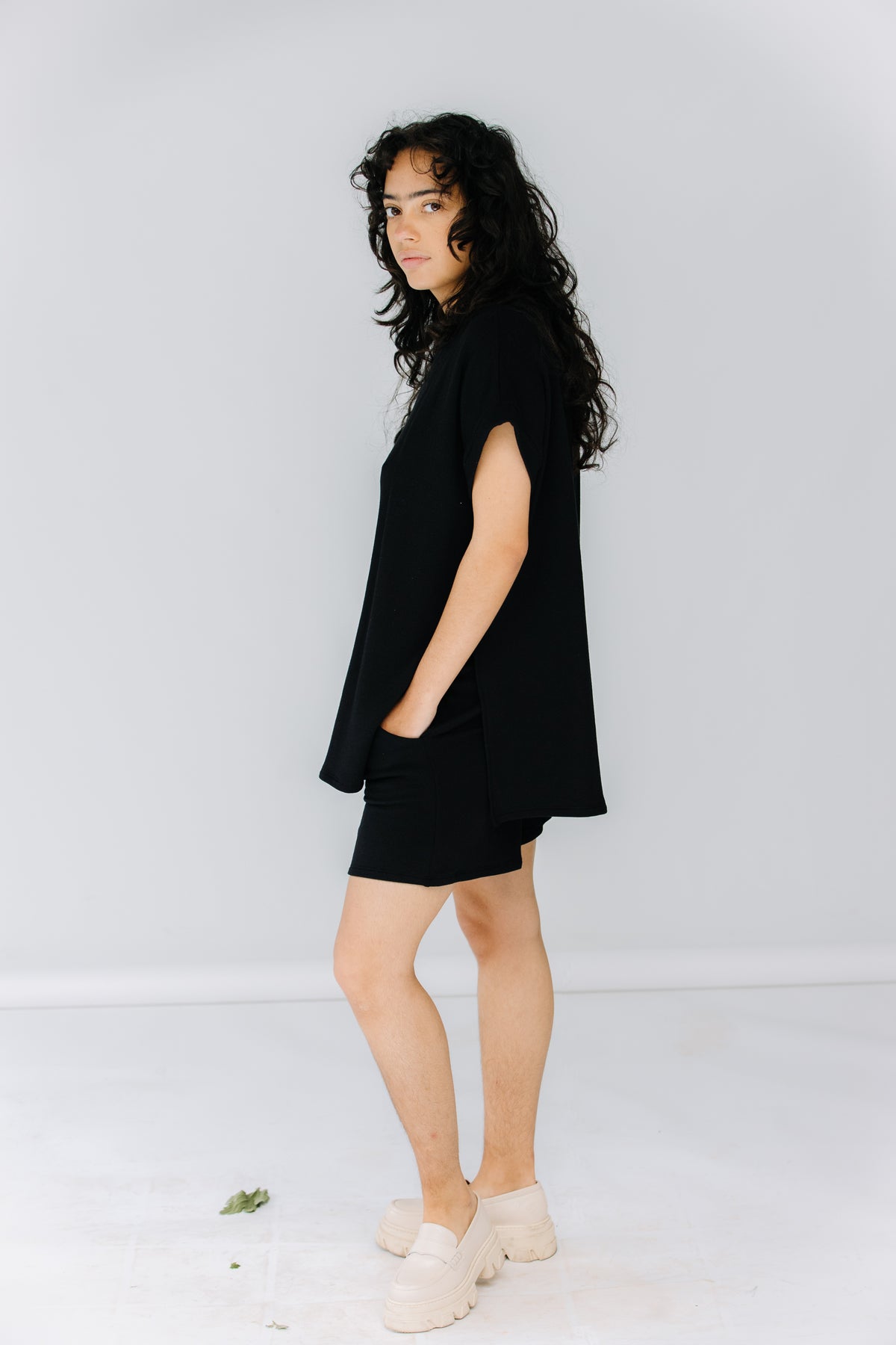 gabby wears the corinne collection siena shorts in black with the ava tunic in black and alohas trailblazer loafers.