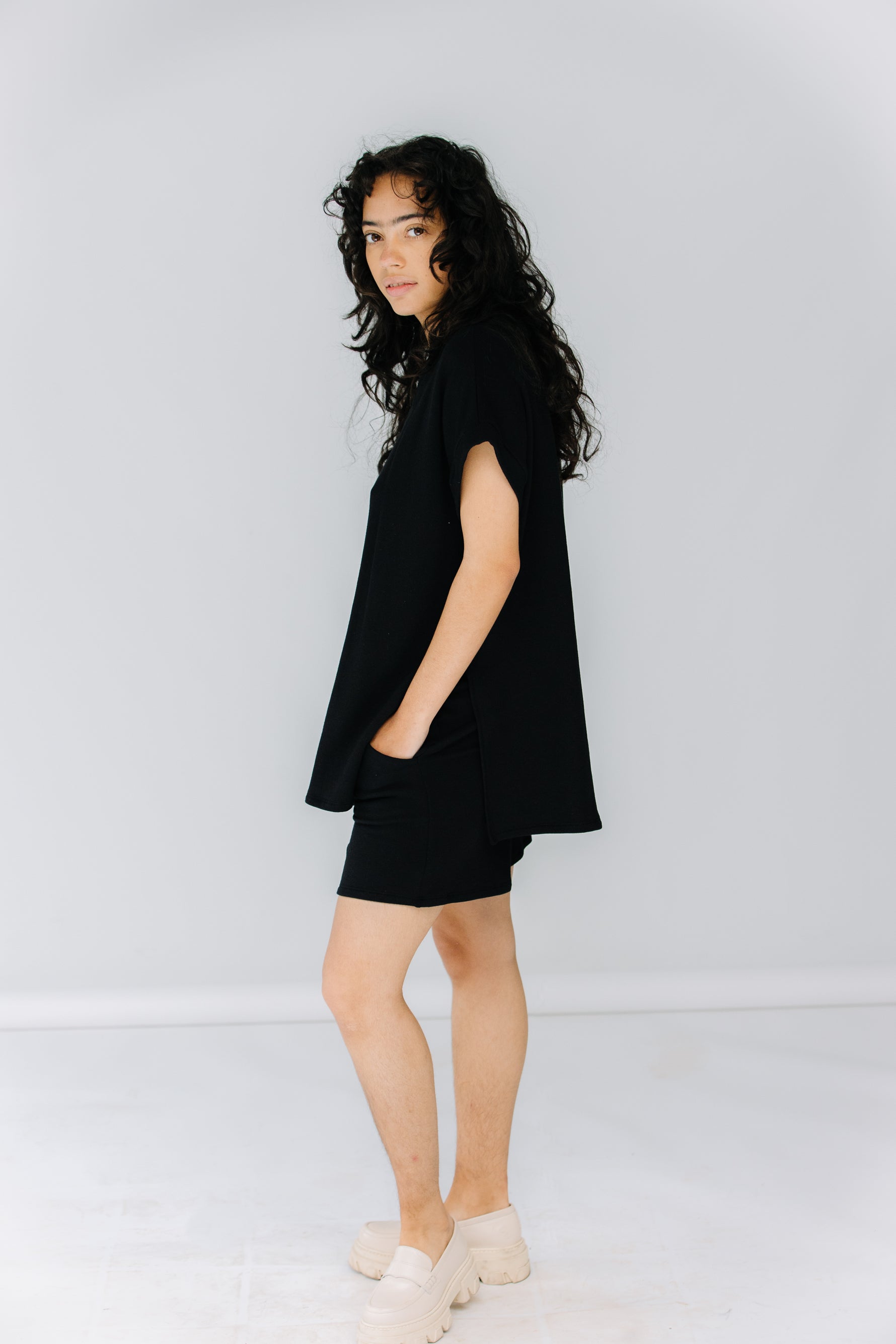 gabby wears the corinne collection siena shorts in black with the ava tunic in black and alohas trailblazer loafers.