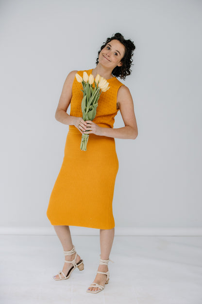 lacey wears the pointelle top and ribbed midi skirt in marigold by mr mittens. she is holding yellow tulips and has aloha creative ivory heels on.