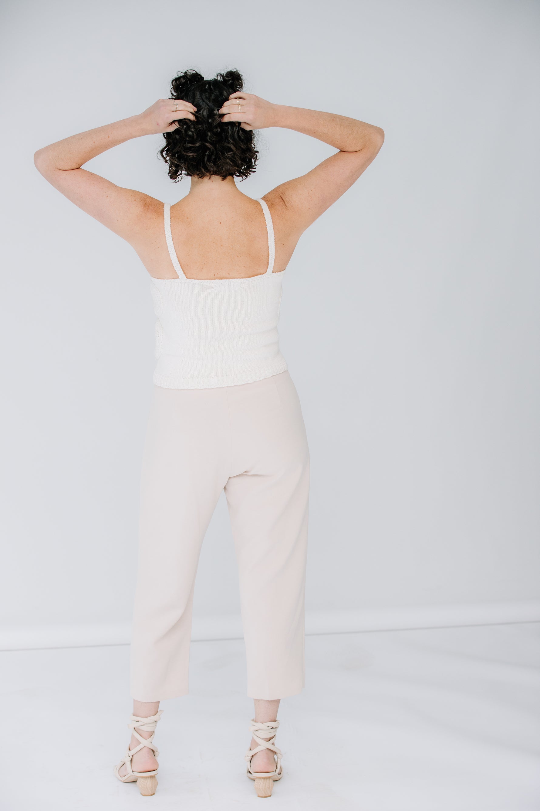 lacey models the lingua franca crochet flower tank in ivory. she is wearing kaarem sua trousers in cream with corresponding alohas sandals.