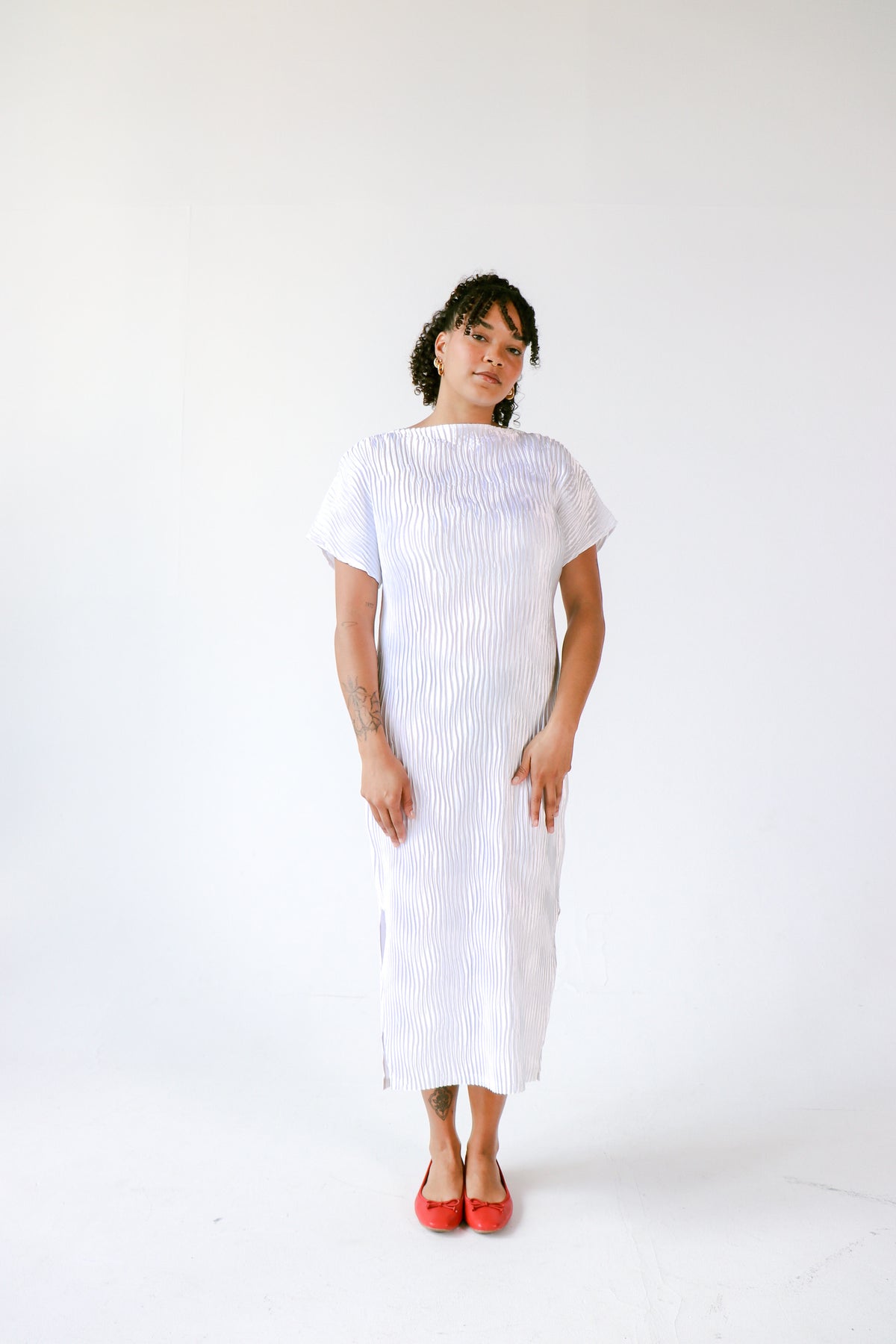 Person wearing a white dress with a subtle pattern on a white background