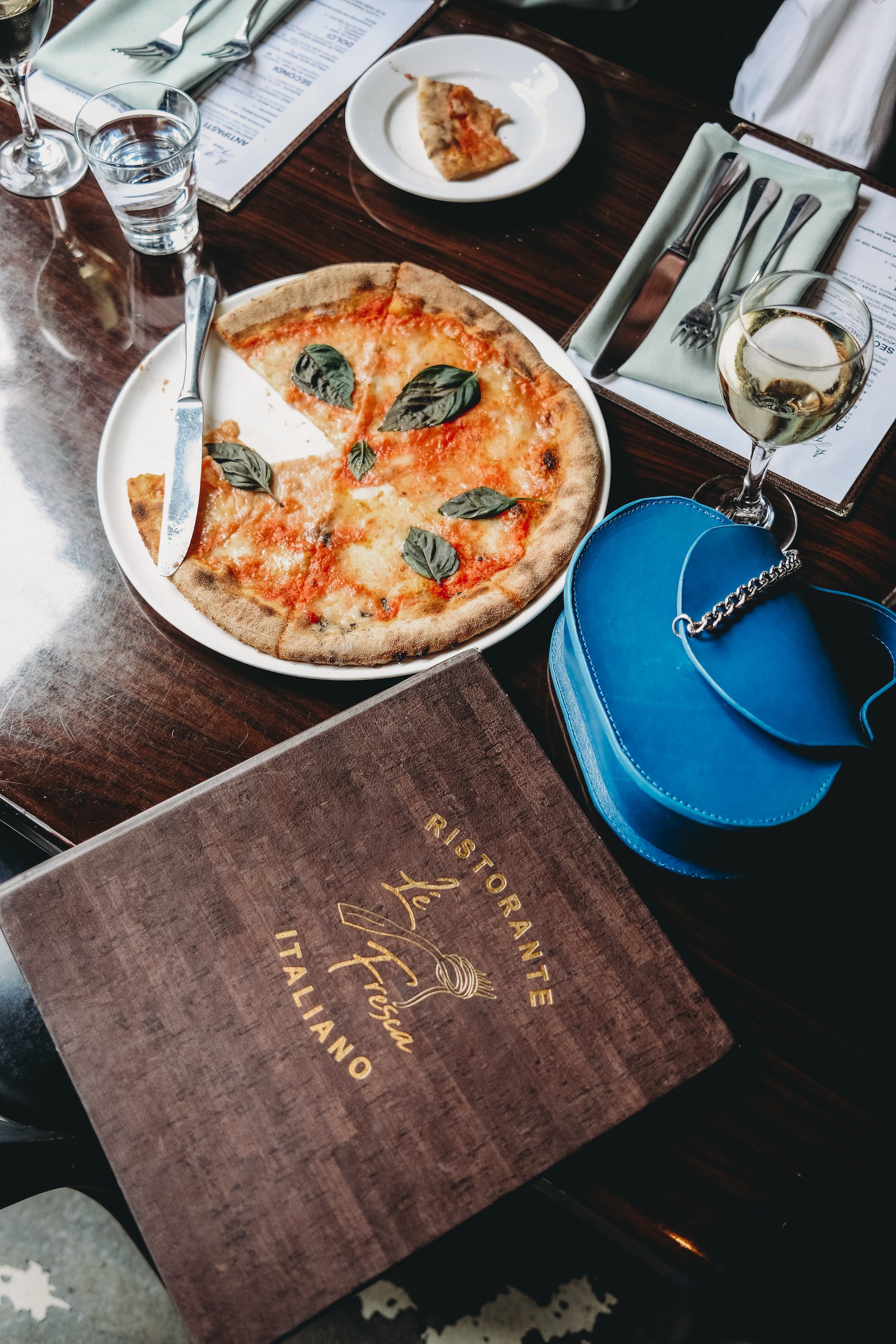 the alcove bag in azul on a table with a pizza and menu