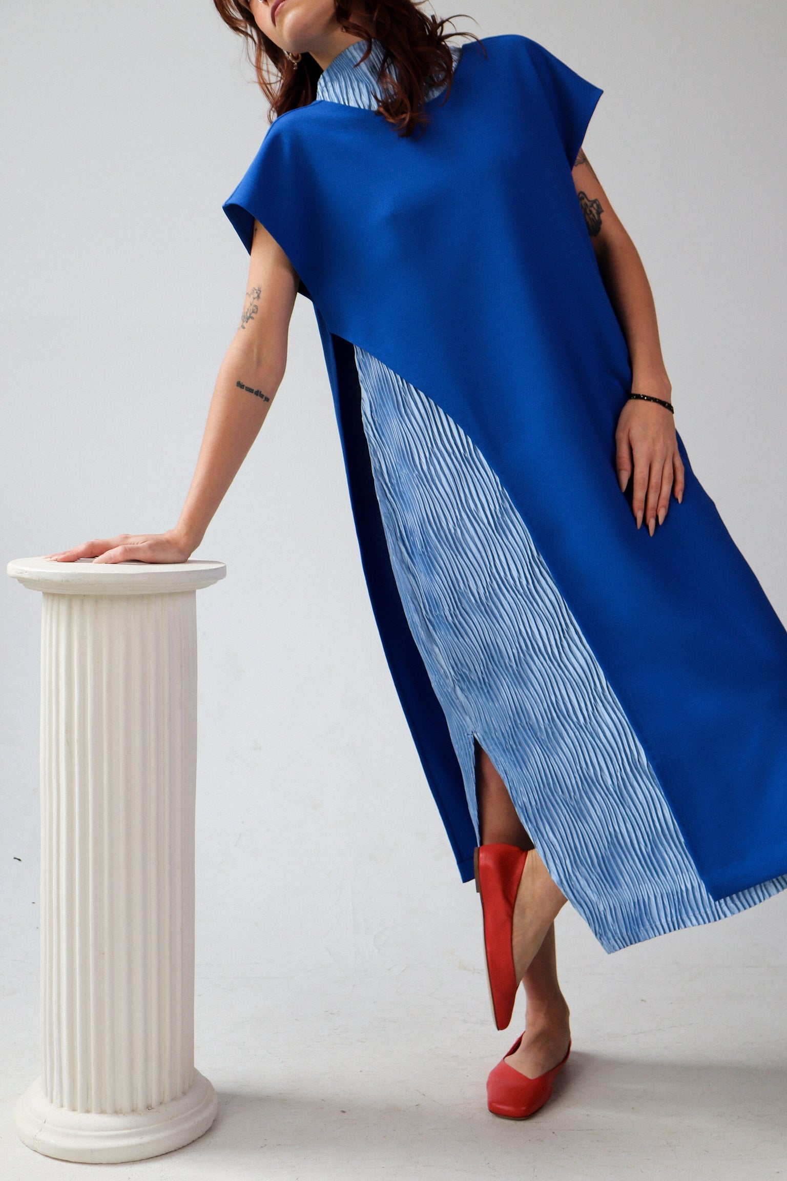 Woman wearing a blue dress with a white pedestal in the background