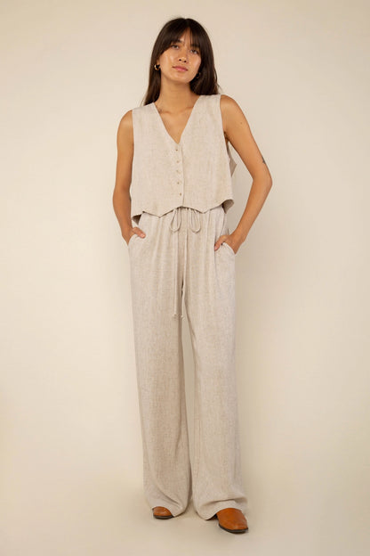 a brunette woman wearing a linen button front vest with matching drawstring pants in natural