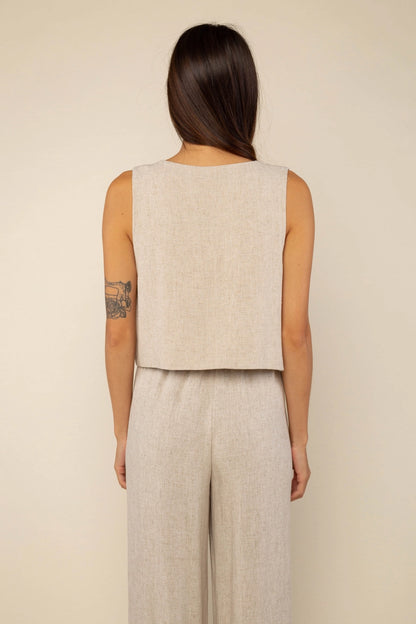 back detail of a brunette woman wearing a linen button front vest with matching drawstring pants in natural