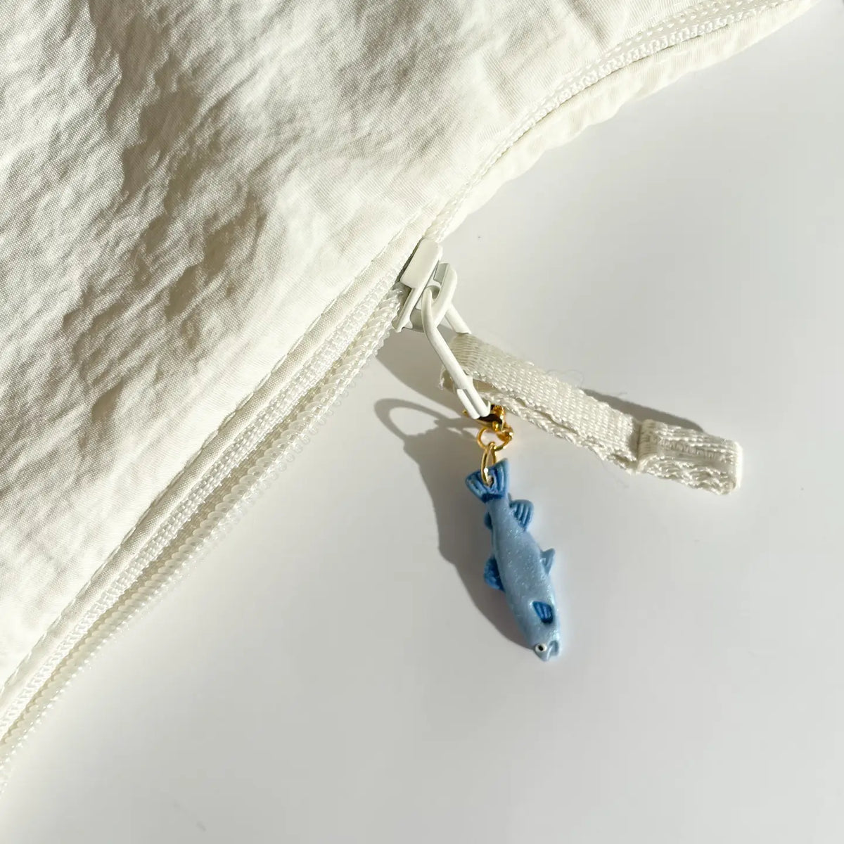 White garment with a blue fish charm on a light gray background