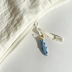 White garment with a blue fish charm on a light gray background
