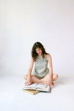 Woman sitting on the floor reading a book against a white background