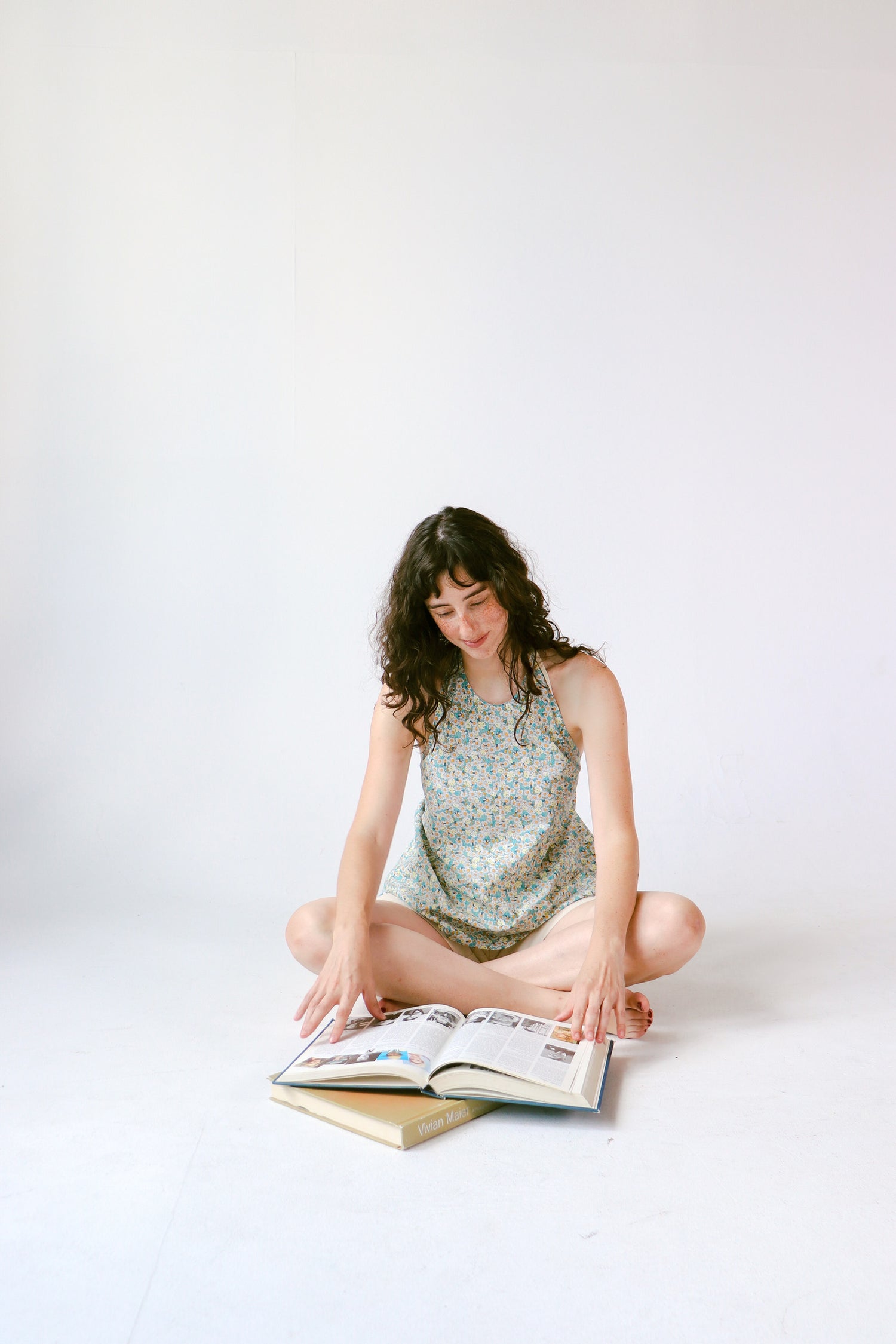 Woman sitting on the floor reading a book against a white background